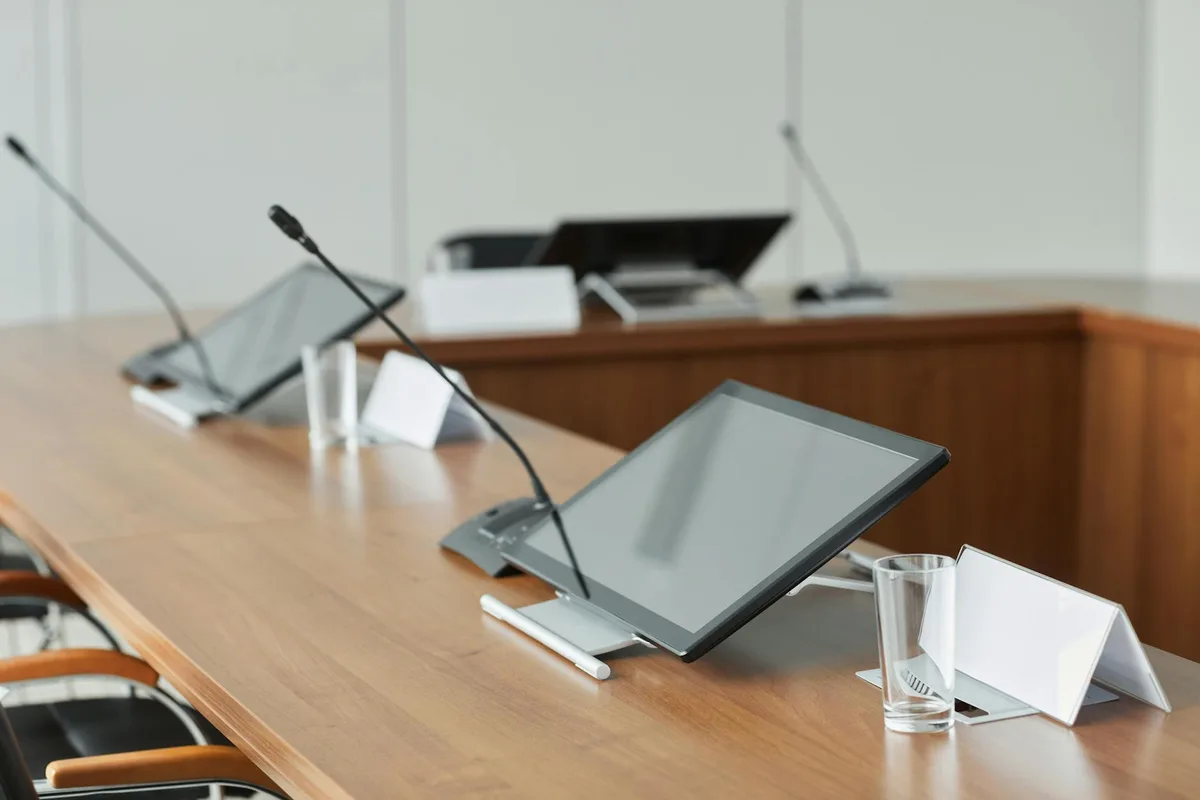 Sala riunioni moderna con monitor e microfoni su tavolo in legno, ideale per meeting