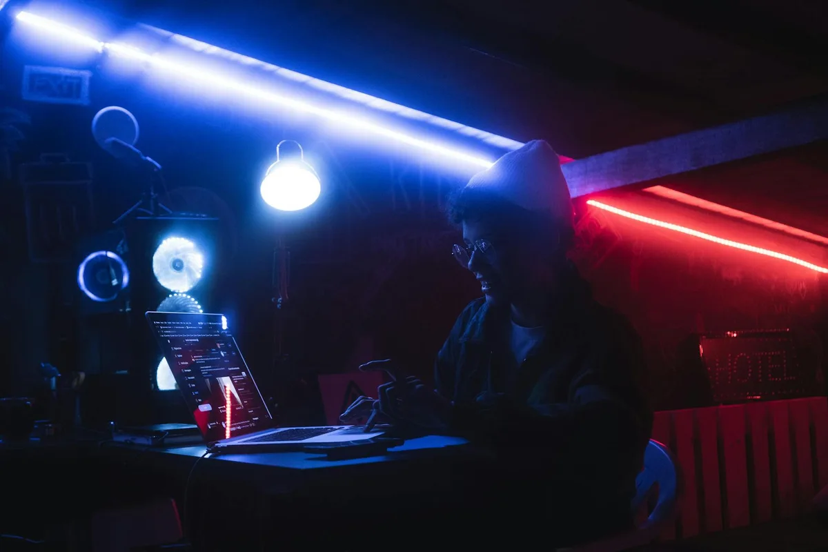 Persona al lavoro su laptop in stanza al neon a San Paolo, atmosfera moderna e vibrante