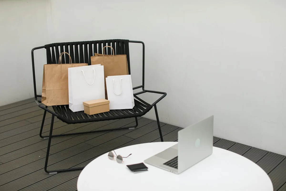 A stylish scene of online shopping with a laptop and various shopping bags on a chair.