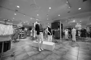 Black and white image of a fashion store interior featuring mannequins and clothing displays.