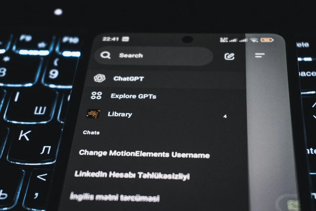 Close-up de smartphone exibindo interface de app de chat com teclado iluminado ao fundo