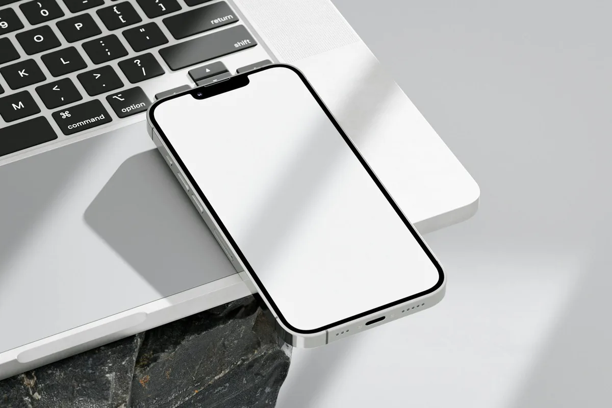 Smartphone-Nahaufnahme auf Laptop mit leerem Bildschirm für Mockup-Nutzung