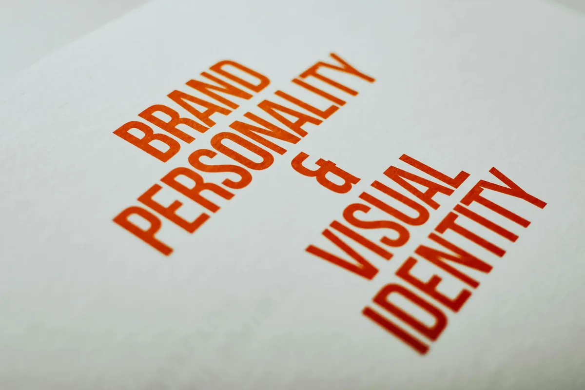 Gros plan sur le texte « Brand Personality & Visual Identity » en rouge sur papier blanc