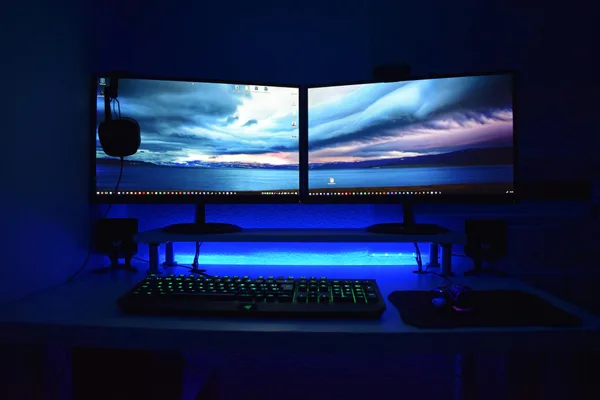 Deux écrans avec éclairage bleu sur un bureau gaming