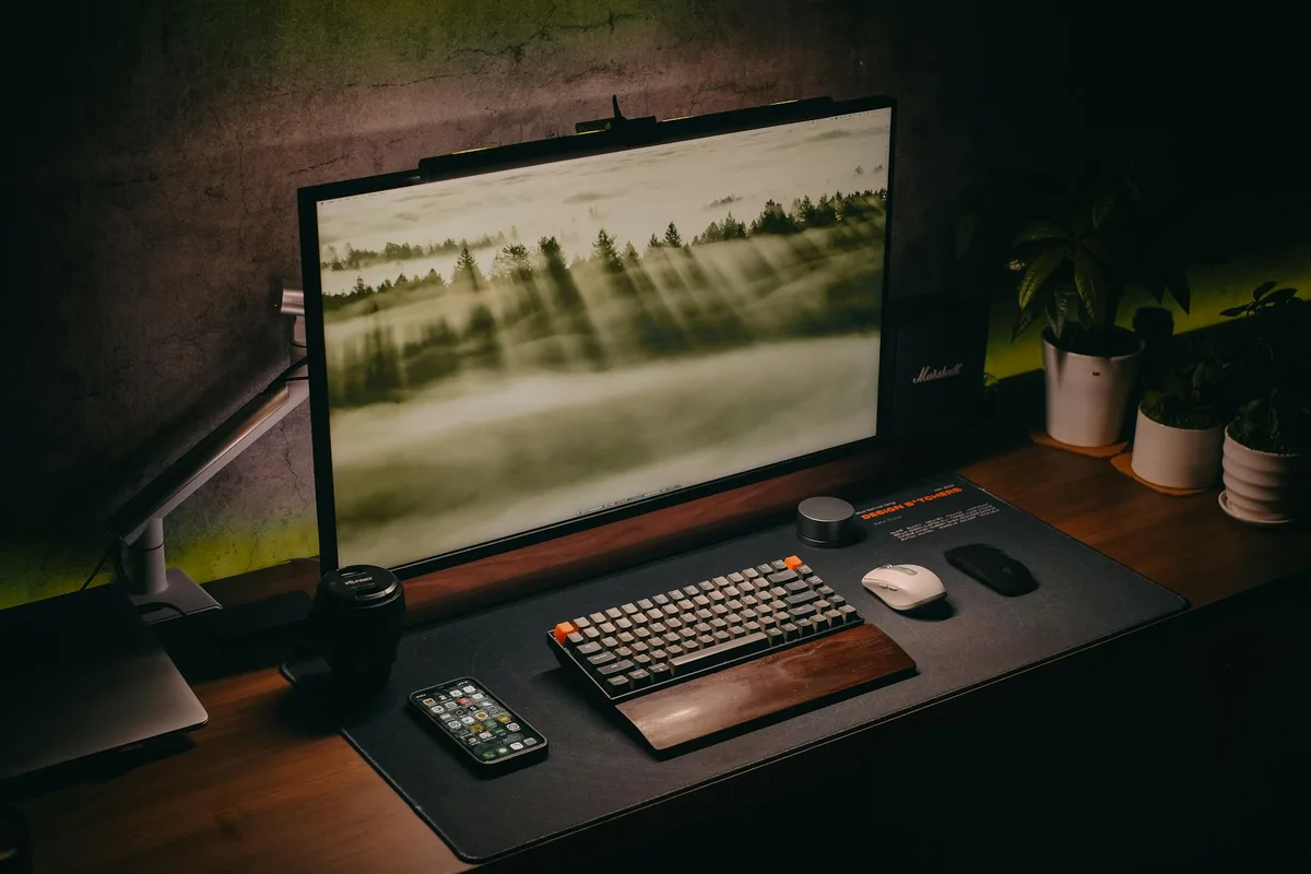 Setup computer elegante con tastiera, monitor e piante su scrivania in legno