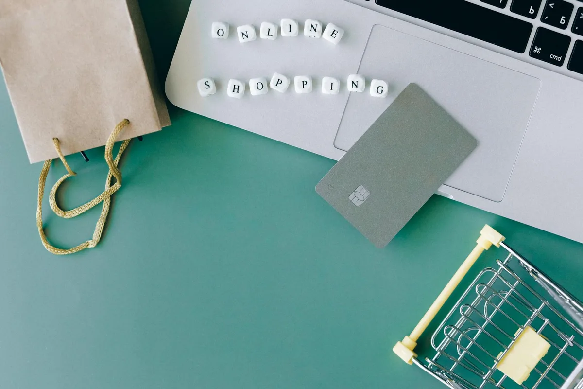 Composizione piatta di shopping online con laptop, carta e carrello