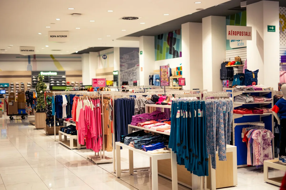Interior of a modern department store with clothing displays and signage, offering a trendy shopping experience.
