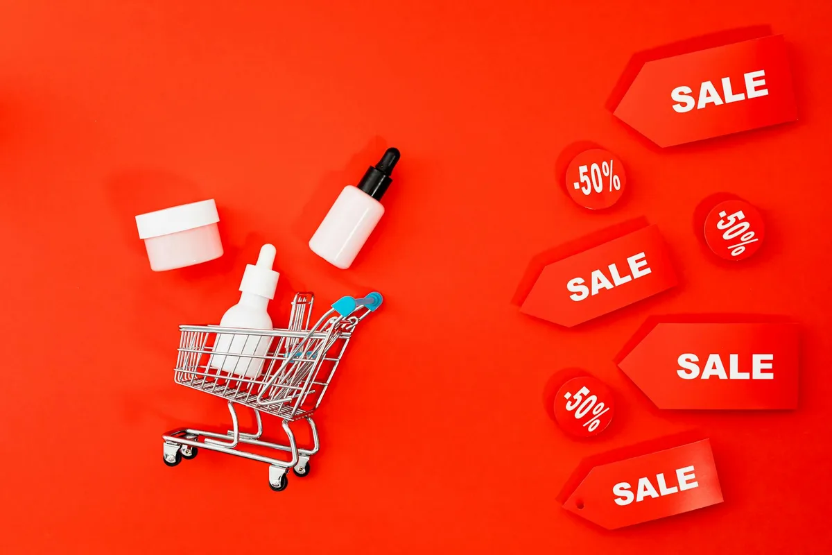 Itens de skincare em minicarrinho com etiquetas de promoção em fundo vermelho para Black Friday.