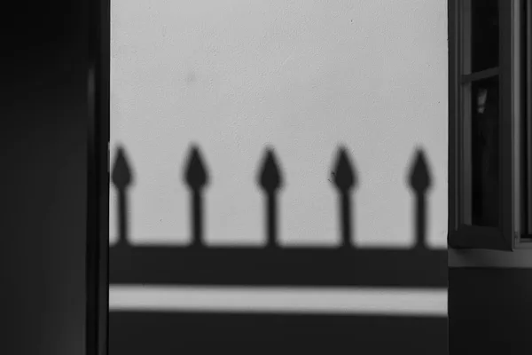 壁に映るフェンスの影が作る幾何学模様の白黒写真