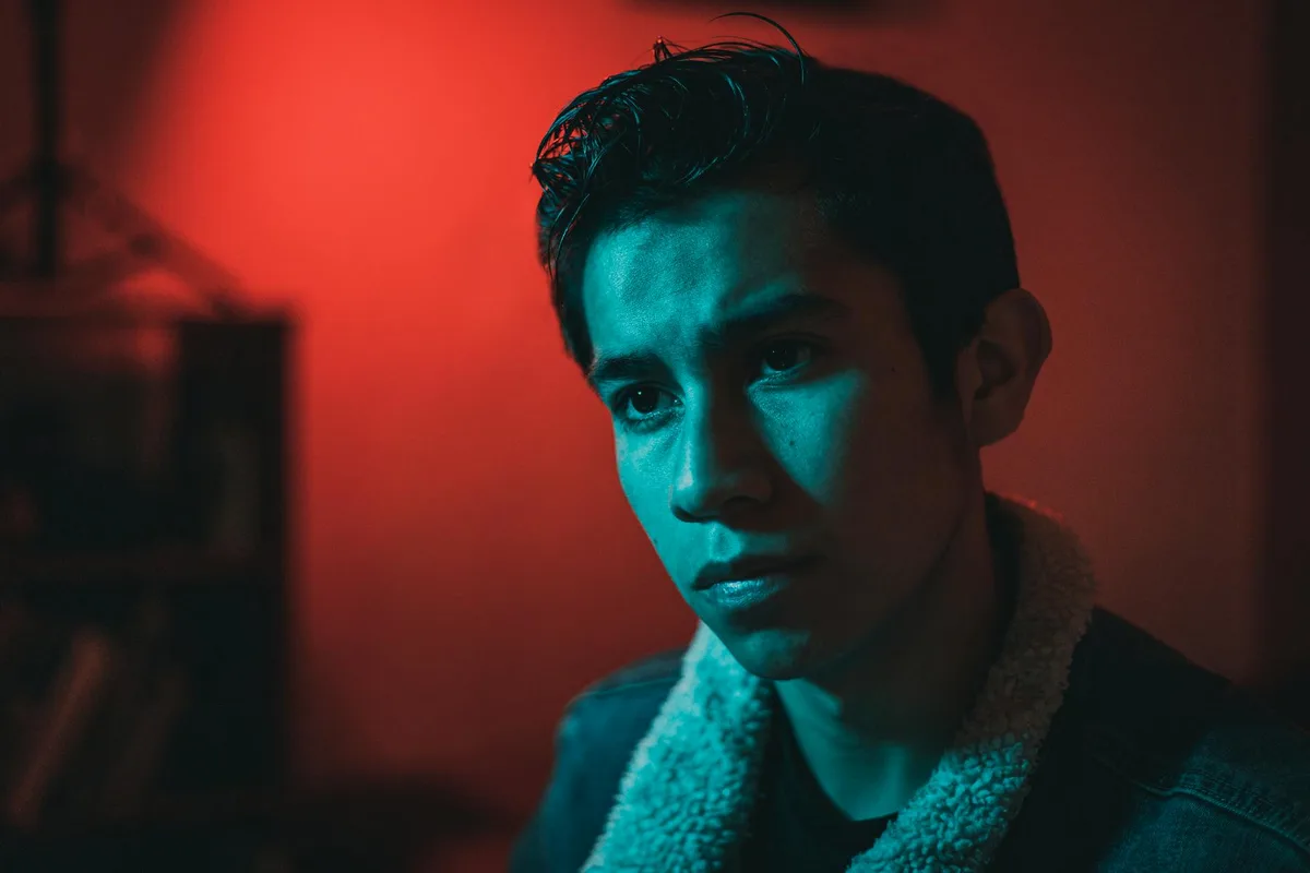 Dramatisches Porträt eines nachdenklichen jungen Mannes unter rot-blauer Beleuchtung
