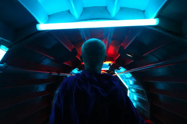 Person geht durch einen futuristischen neonbeleuchteten Tunnel in Brüssel, Belgien