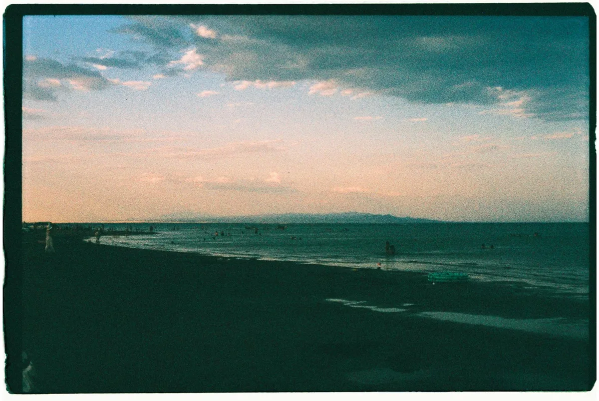 Ruhige Strandszene bei Sonnenuntergang mit Silhouetten und pastellfarbenen Himmelsnuancen im Filmstil