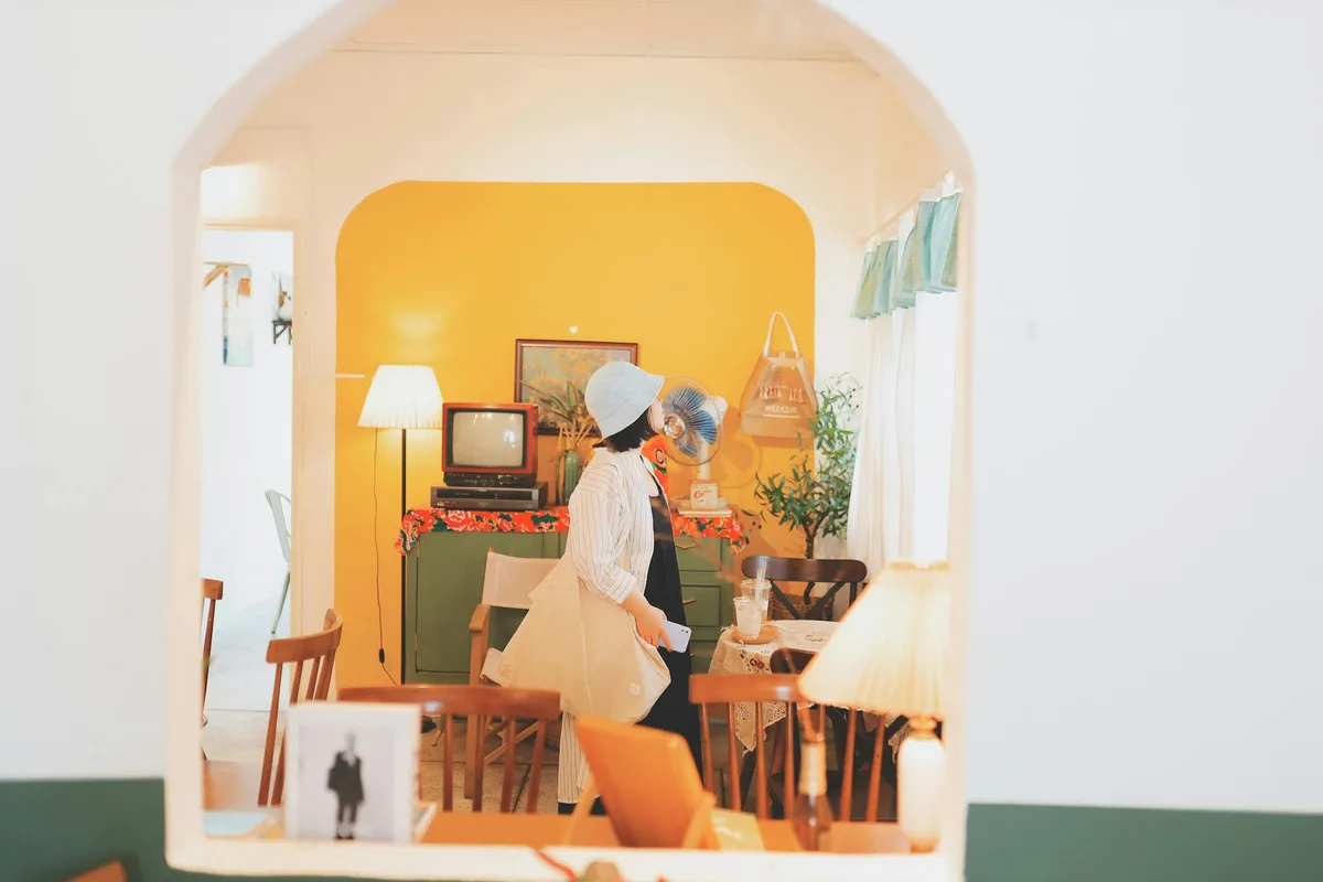 Femme en chapeau bucket explorant une pièce vintage chaleureuse au Vietnam