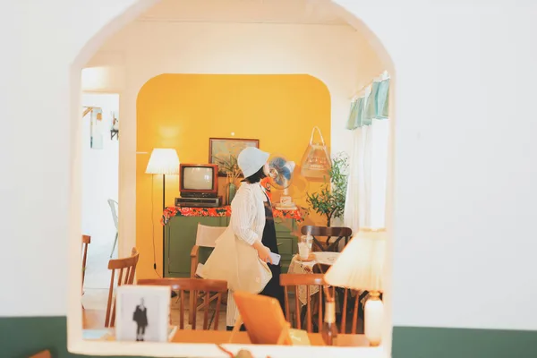 Frau mit Bucket-Hat erkundet gemütlichen Vintage-Raum in Vietnam