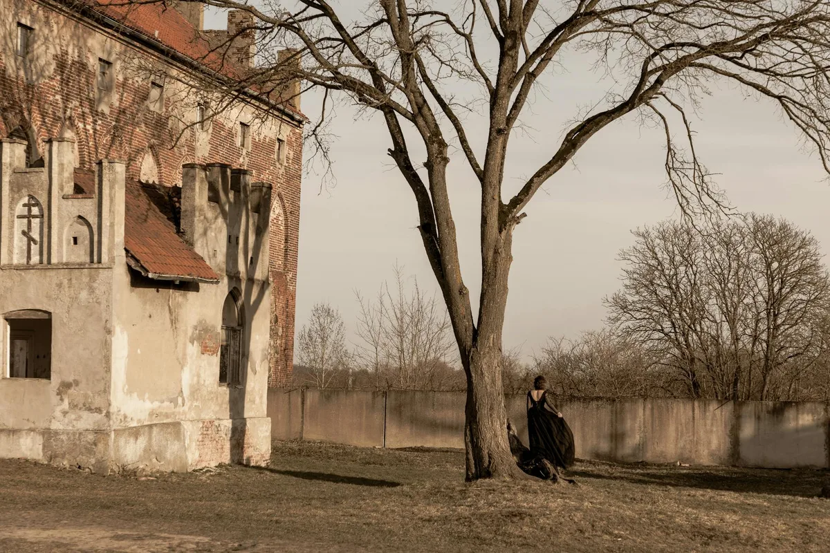 冬の歴史的建造物のそばで黒い衣装の女性が立つシーン