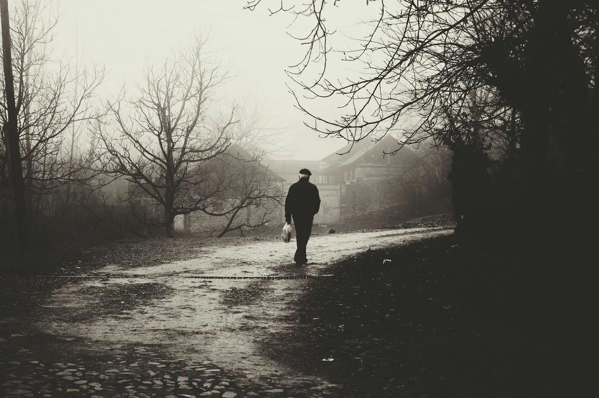 Silhouette d’une personne marchant dans une rue déserte et brumeuse, mystère et solitude