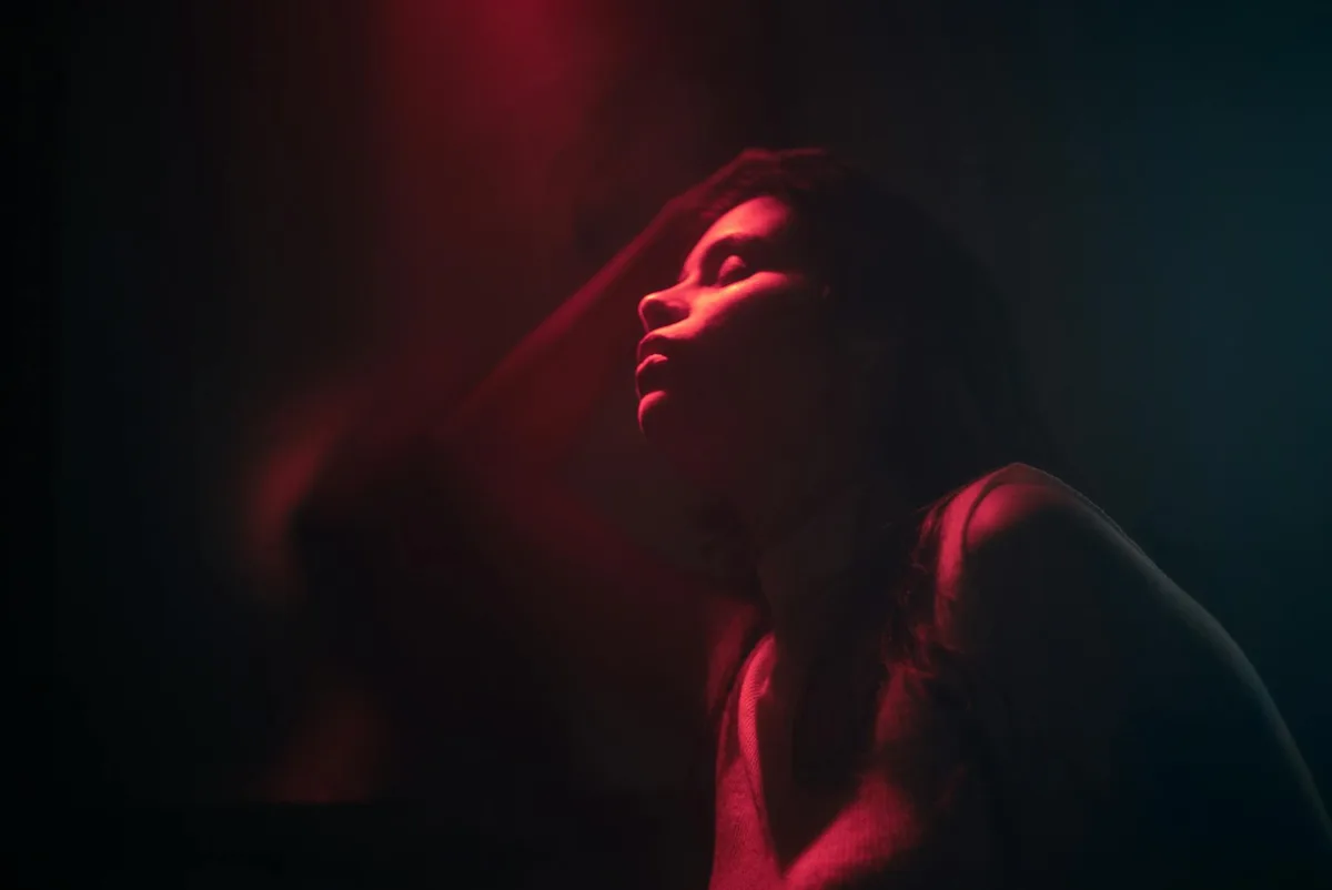 Ritratto artistico di donna, luci rosse e ombre.