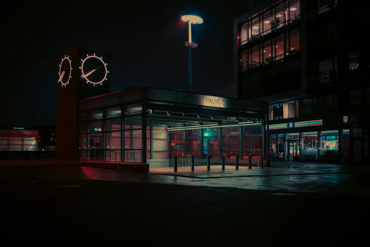 Atmosphärische Nachtansicht des Malmö C Bahnhofs mit Neonlichtern und Reflexionen