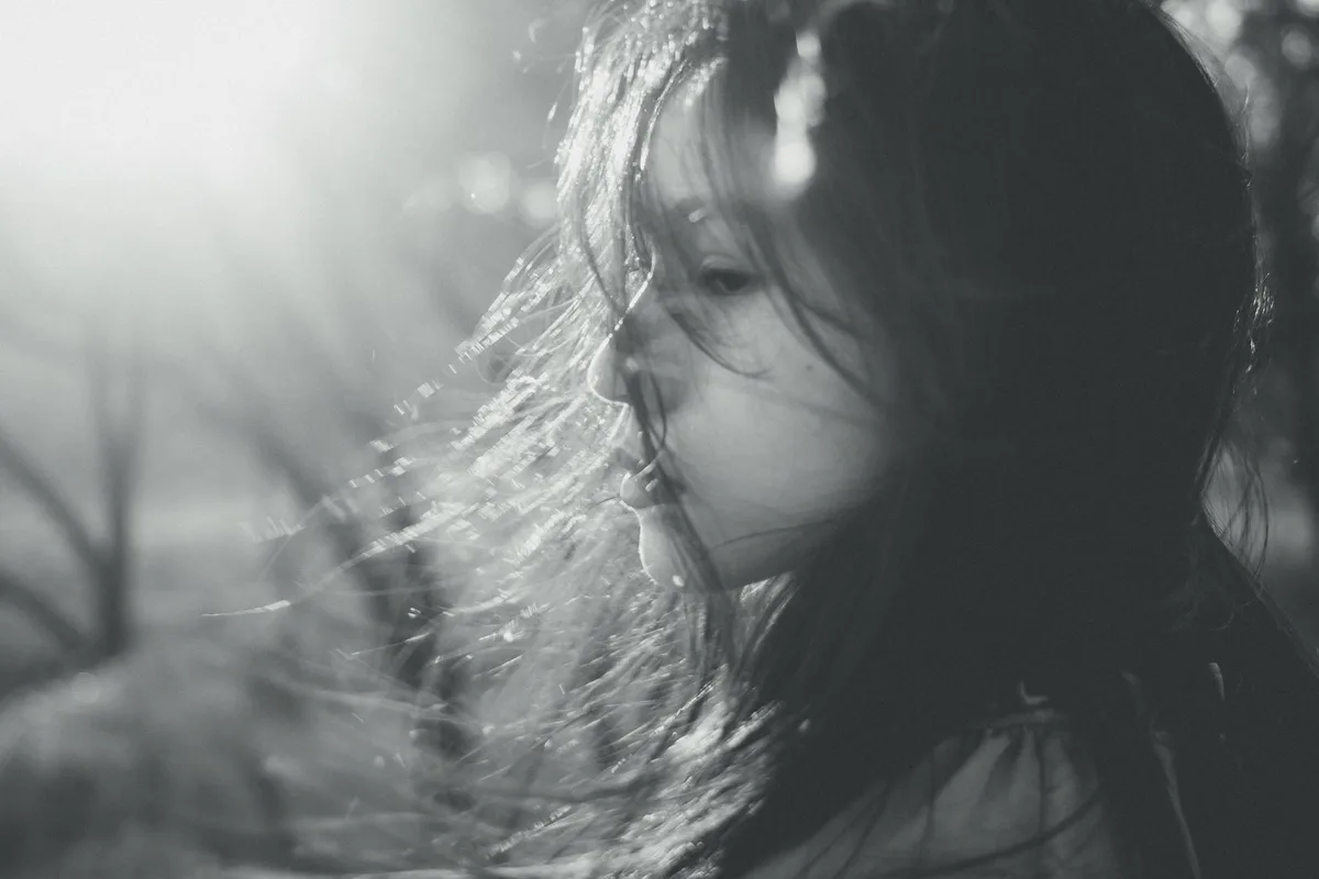 Schwarz-Weiß-Seitenprofil einer Frau mit windzerzaustem Haar, ruhige Stimmung
