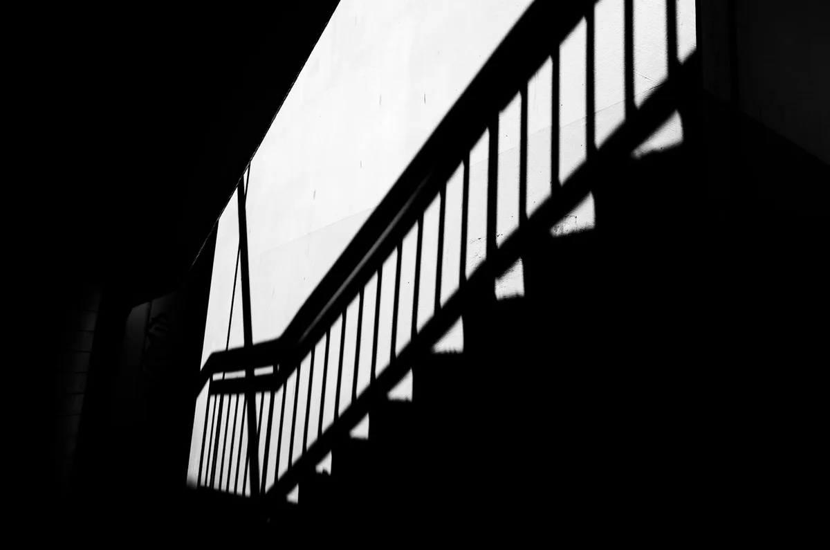 Monochromfoto von Treppenschatten, die geometrische Muster an einer Wand bilden