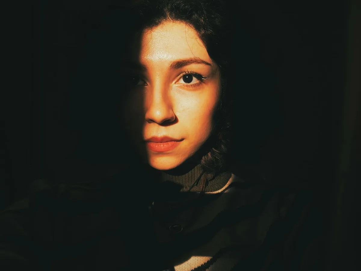 ドラマチックな影と暖かい照明で片側の顔が強調された女性のムーディーな肖像