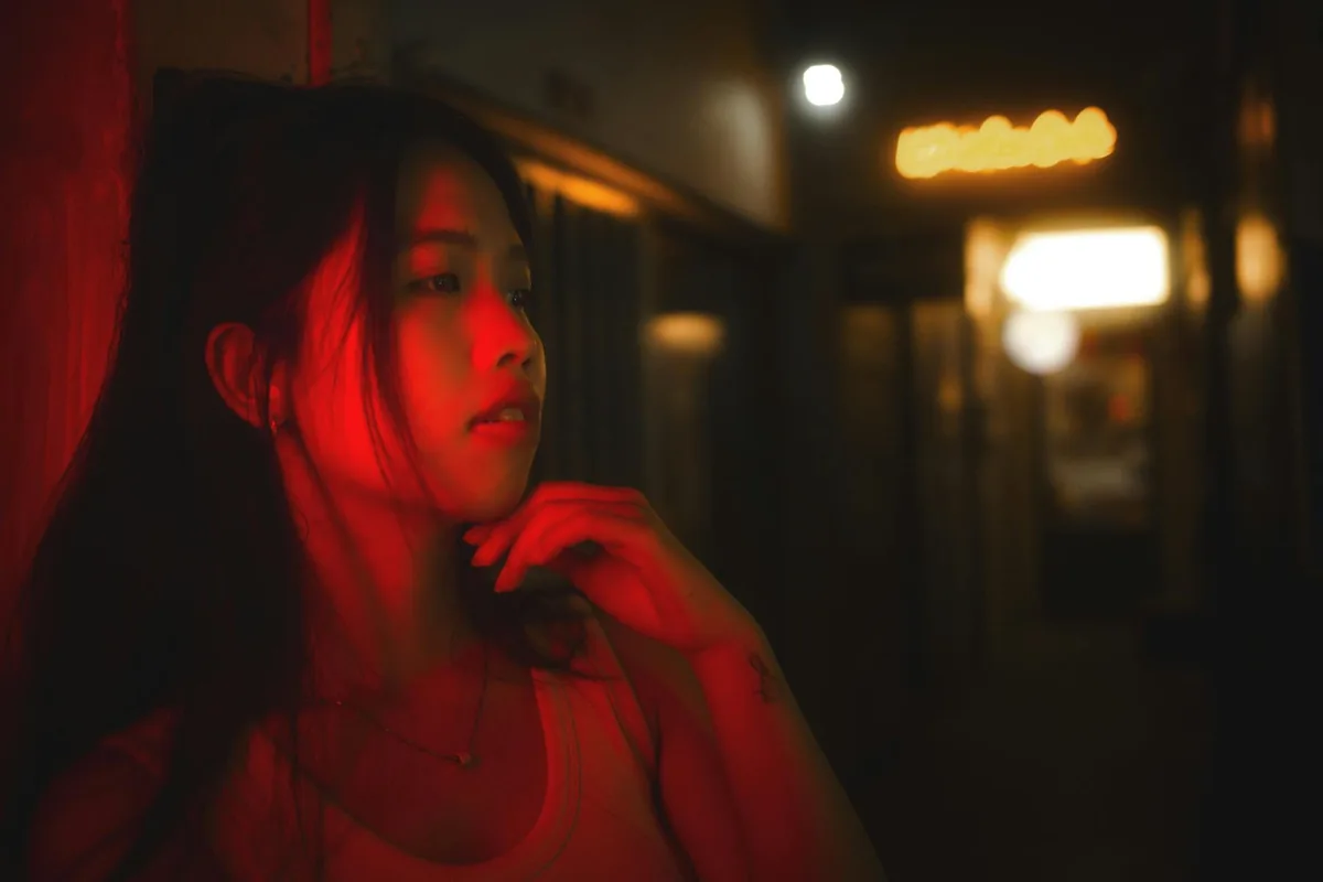 Portrait stylisé d'une femme sous néon rouge dans un couloir sombre