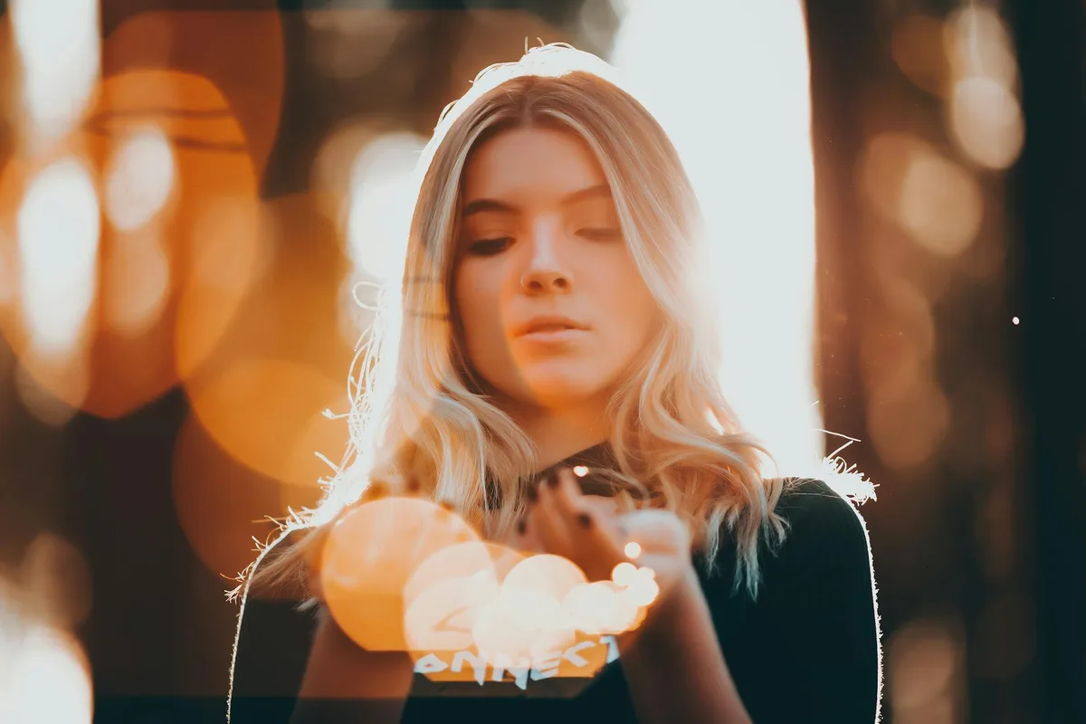Mujer joven con luces de hadas en fondo bokeh, retrato cálido y etéreo