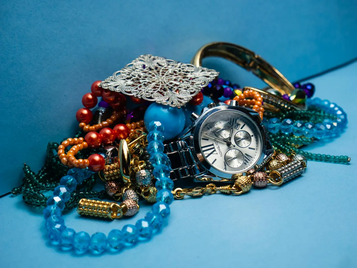 ブルーの背景にカラフルなジュエリーとスタイリッシュな腕時計を並べたクローズアップショット