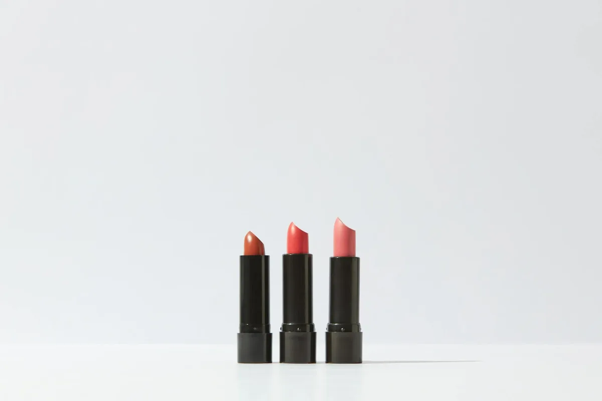 Eine minimalistische Darstellung von drei Lippenstiften auf weißem Hintergrund, perfekt für Kosmetik-Themen.