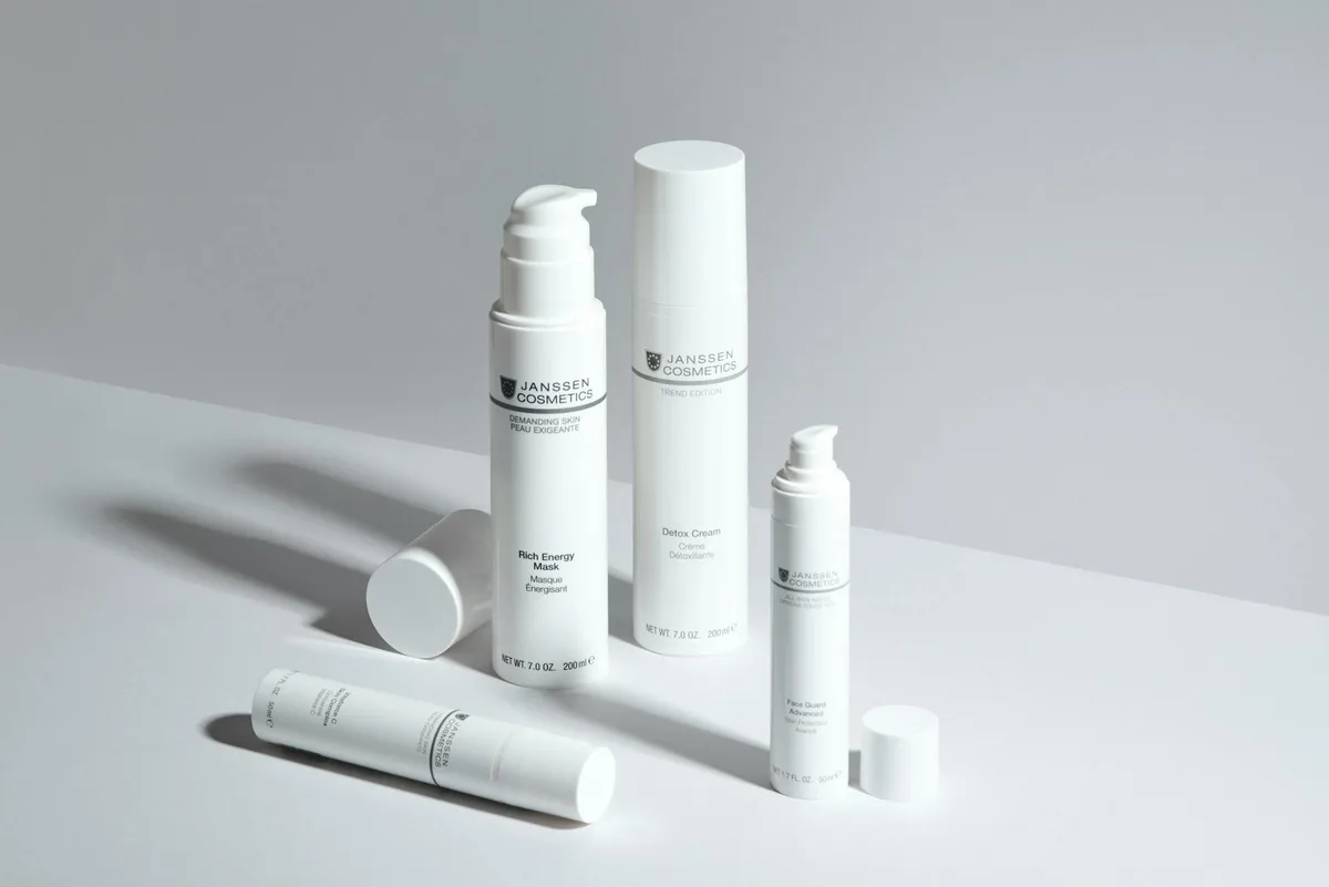 Display minimalista de frascos de skincare Janssen Cosmetics em fundo branco