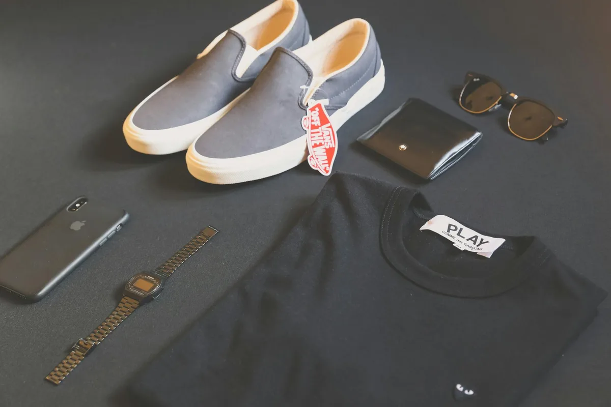 Modernes Flat Lay mit Herrenmode-Essentials: Schuhe, Uhr, Handy und Brille für einen eleganten Stil