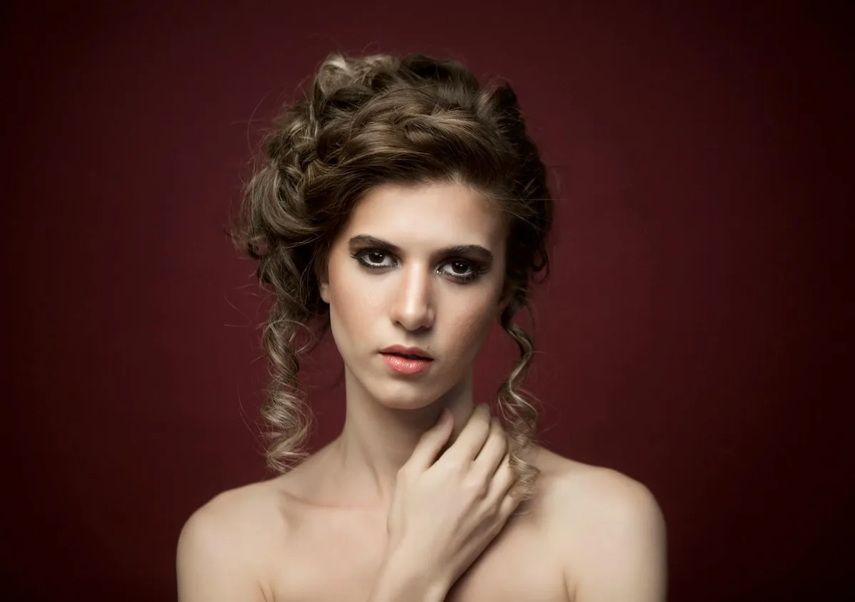 Retrato de mulher com cabelo cacheado estiloso contra fundo vermelho escuro