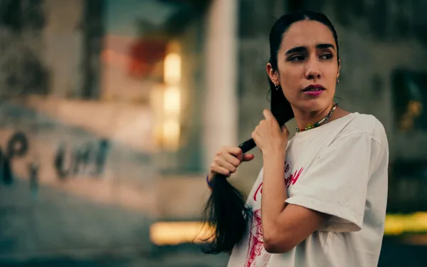 Junge Frau richtet ihre Haare im Freien in Buenos Aires, urbaner Stil
