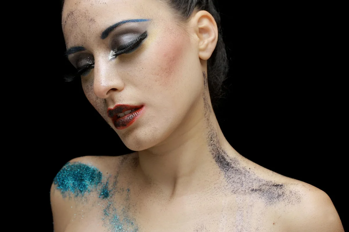 Portrait artistique d'une femme avec maquillage pailleté sur fond sombre
