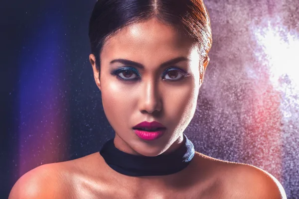 Ritratto femminile con make-up audace e illuminazione drammatica