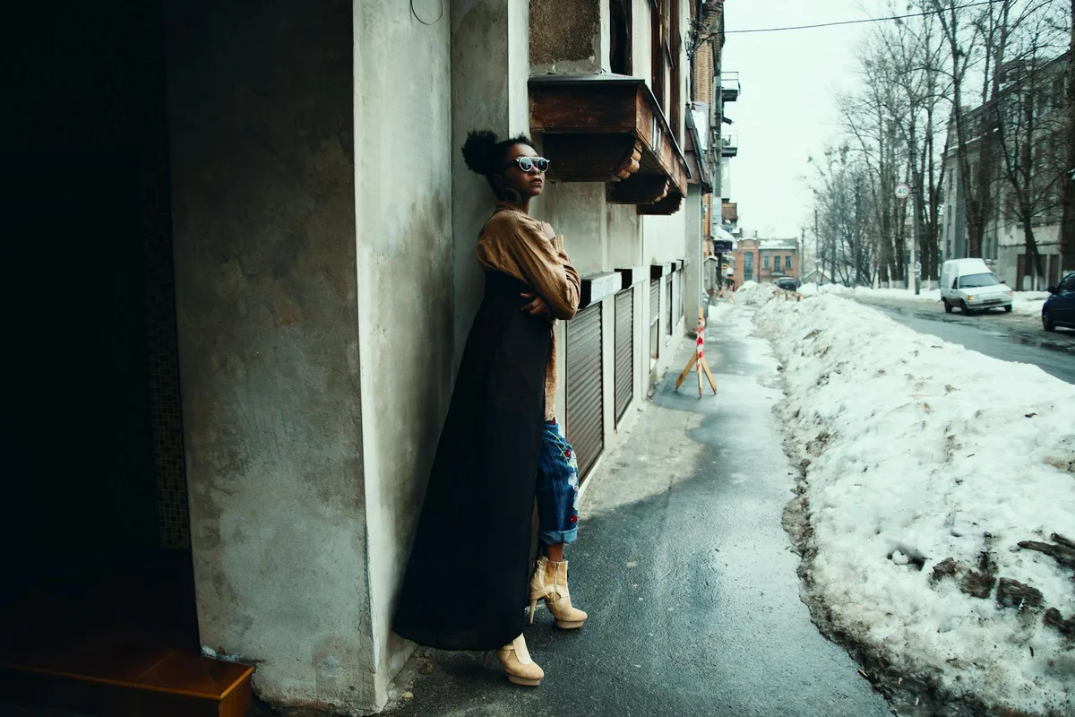 Donna chic in posa in ambiente urbano innevato con occhiali da sole e outfit alla moda