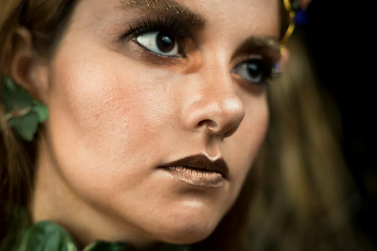 Nahaufnahme einer Frau mit künstlerischem Make-up und naturinspirierten Kopfschmuckstücken