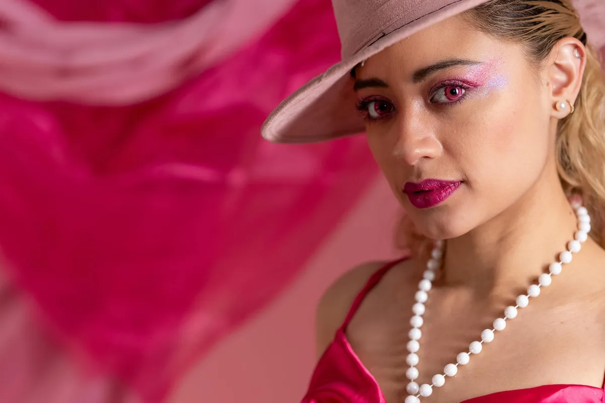 핑크 의상과 모자, 강렬한 메이크업의 우아한 여성 클로즈업