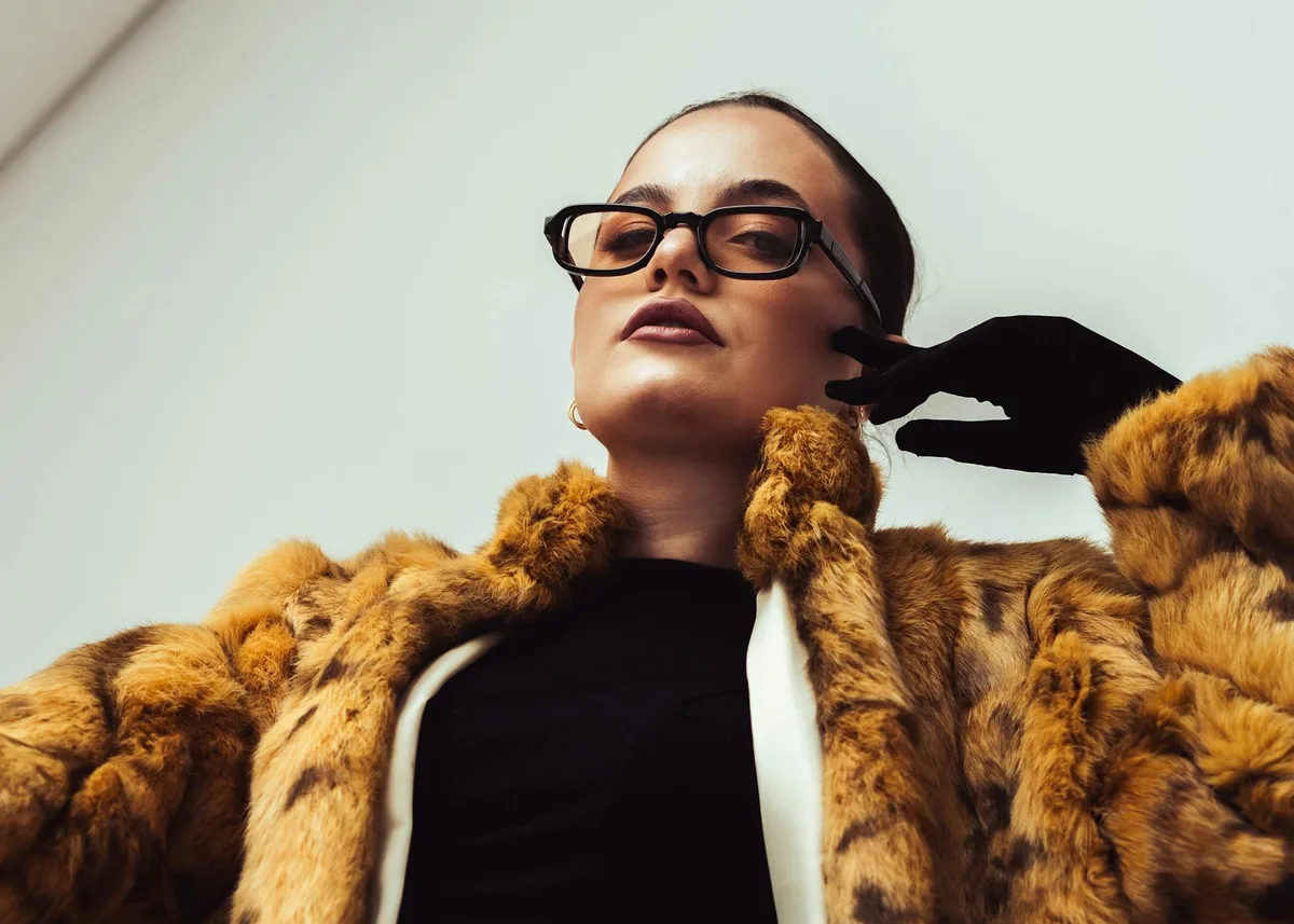 모피 코트와 안경, 당당한 포즈의 우아한 여성 실내 사진