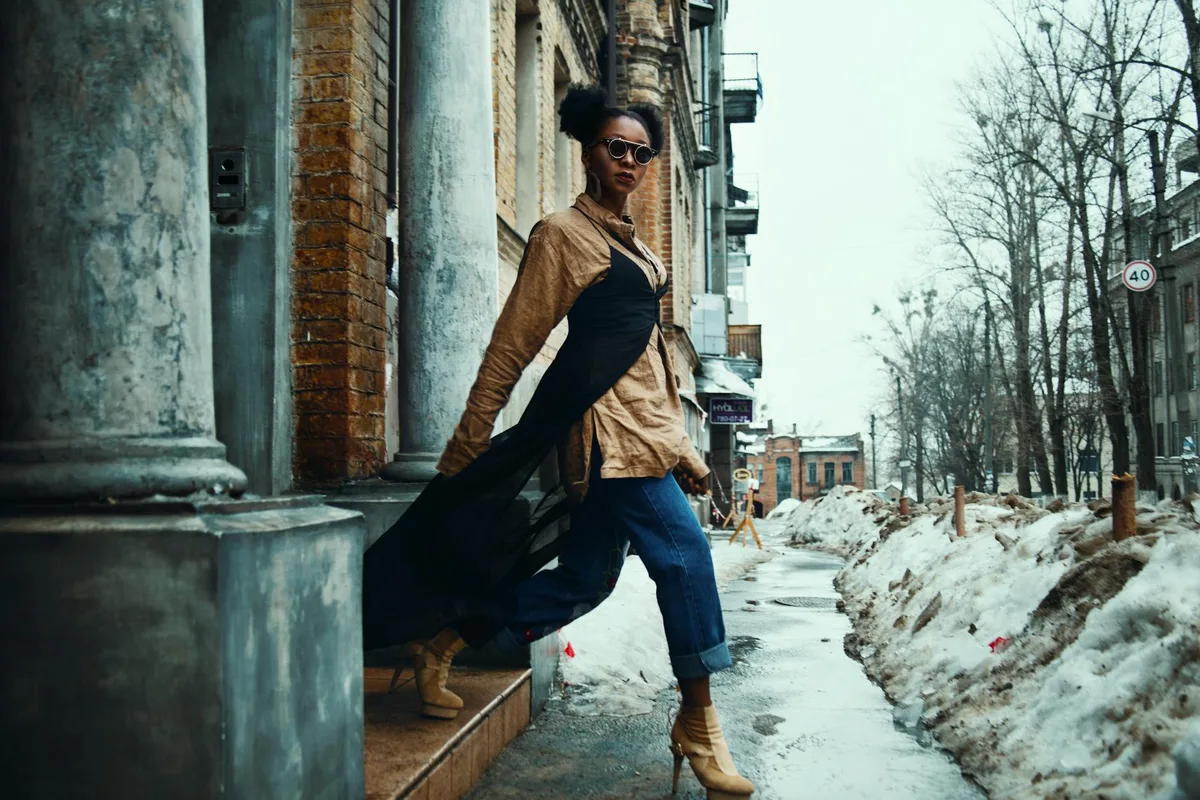 Модная женщина в трендовом образе уверенно позирует на снежной улице