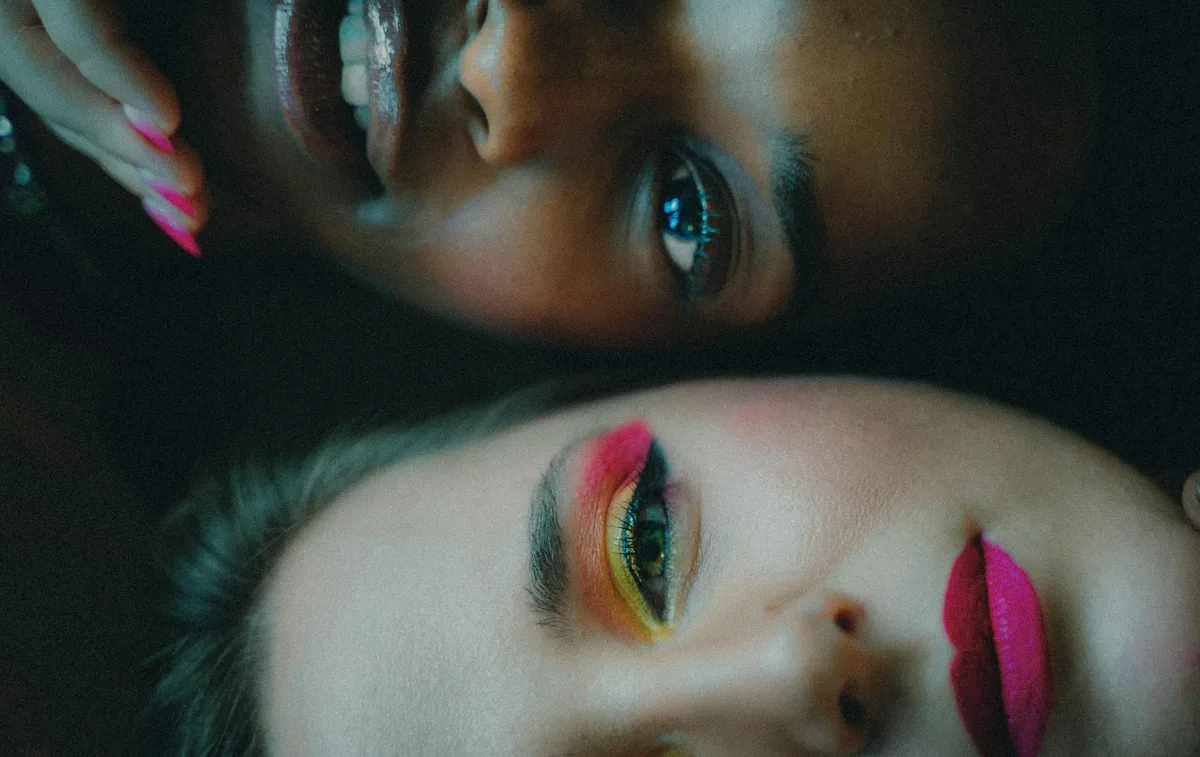 Retrato intimista de duas mulheres com maquiagem colorida, mostrando diversidade e beleza.