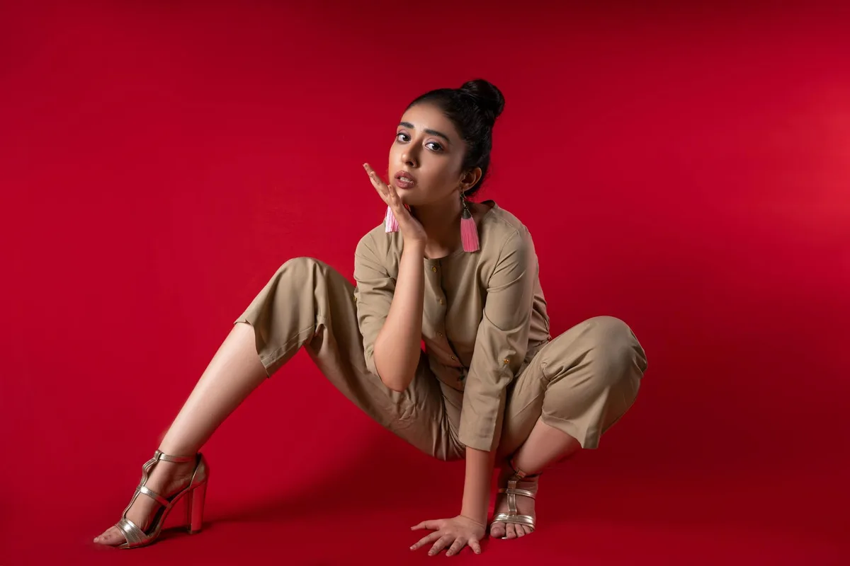 Portrait de mode moderne d'une femme posant devant un fond rouge vif