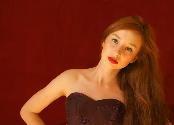 Ritratto donna con capelli rossi e rossetto su sfondo scuro