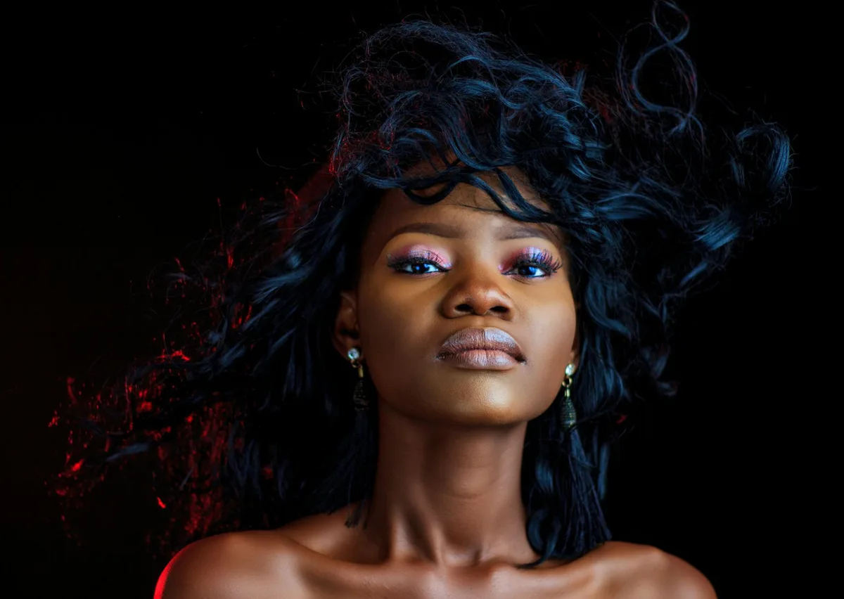 Ritratto sorprendente di donna sicura con illuminazione drammatica e acconciatura