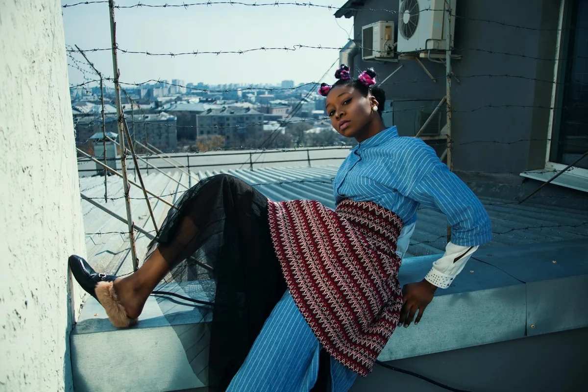 Stilvolle Frau auf einem Dach mit urbanem Hintergrund posiert