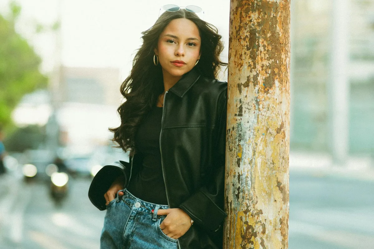 Stilvolle junge Frau in Lederjacke posiert auf einer Stadtstraße