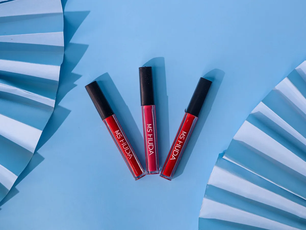 Три красные помады на синем фоне с изящными акцентами в виде вееров