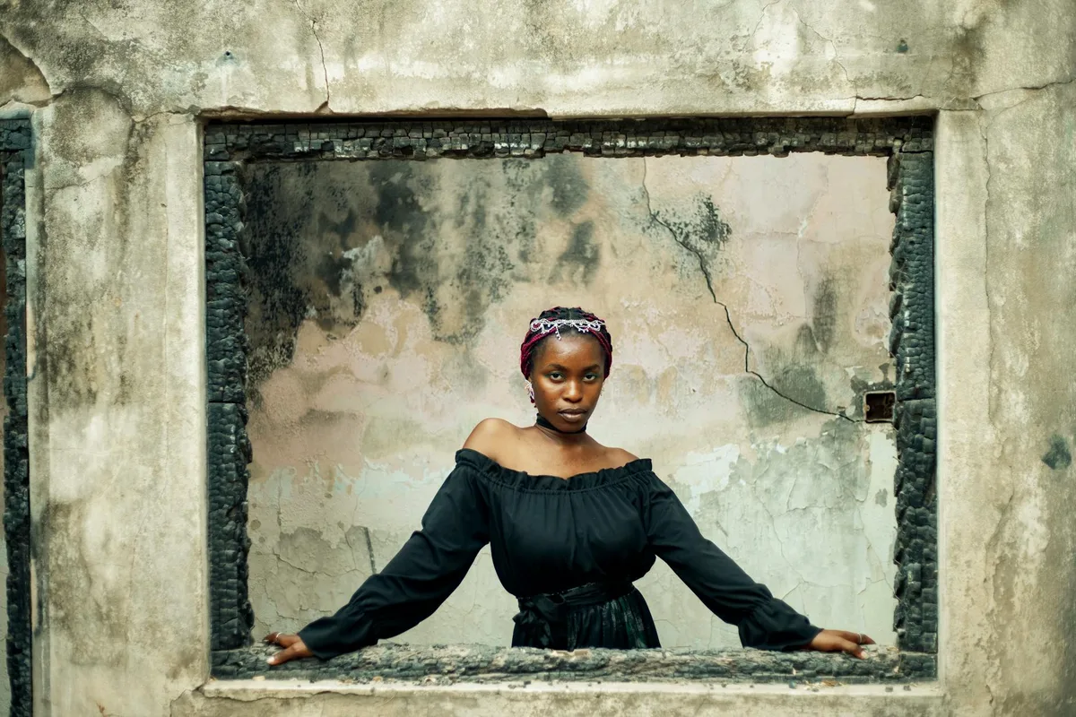 Donna in posa su finestra rustica con sfondo artistico