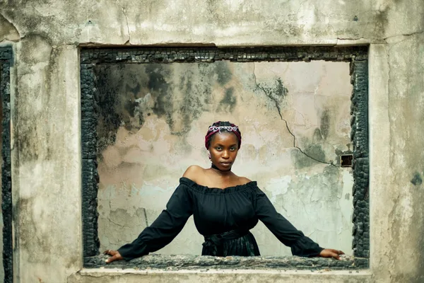 Frau posiert in rustikalem Fensterrahmen mit künstlerischem Hintergrund