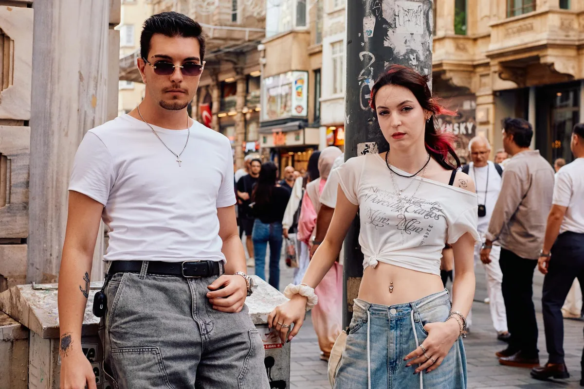 Jovens posam com estilo em rua movimentada de Istambul, destacando o streetwear casual.